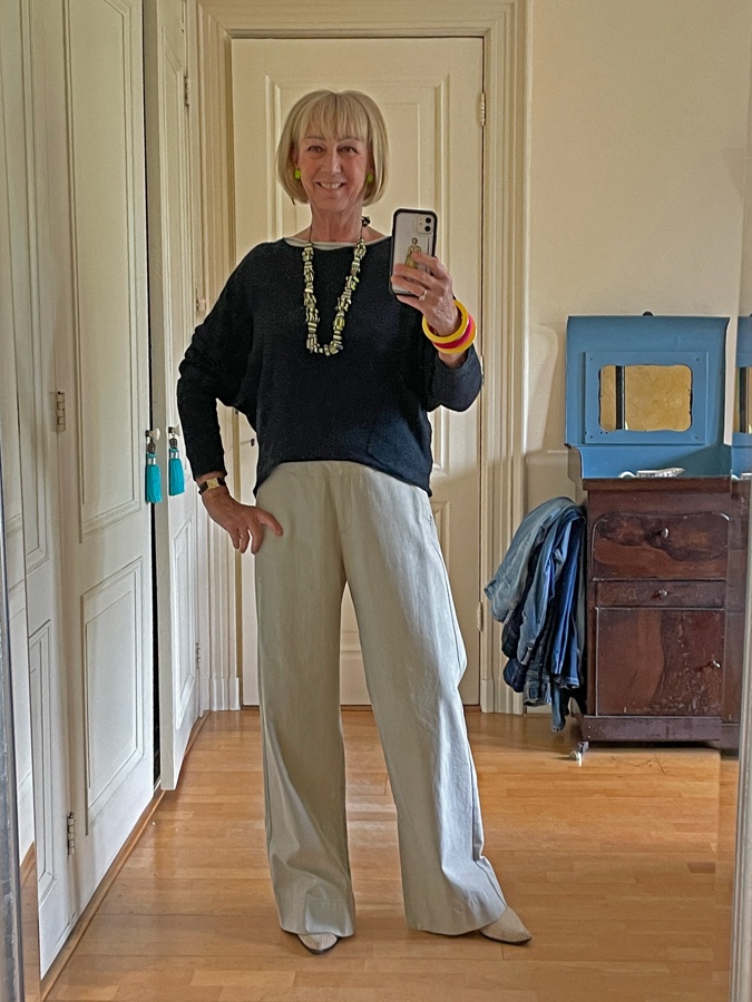 Pebble coloured trousers with a colourful necklace