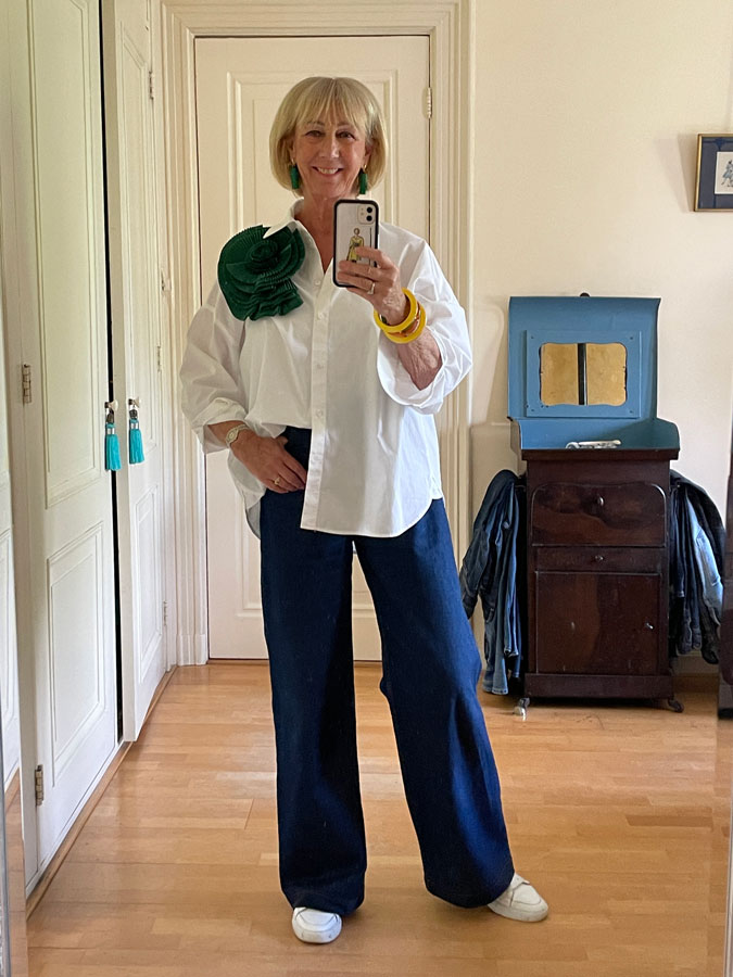 Jeans and a white shirt with a big green rosette brooch