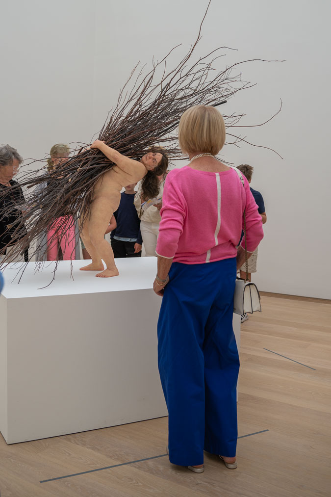 Bright blue trousers with a pink top and Ron Mueck